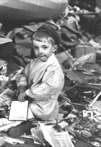Fotografia storica in bianco e nero: un bambino tra materiali di recupero