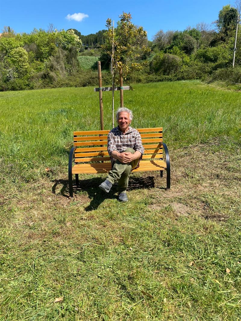 Una persona seduta su una panchina in un giardino